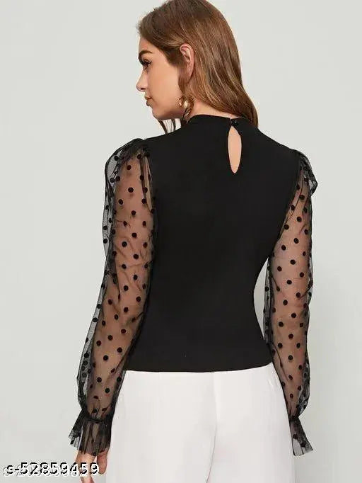 black top with sheer, polka dot sleeves and white pants. The style is elegant and modern, conveying a chic vibe.