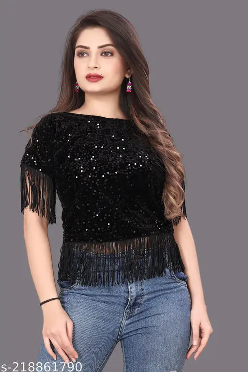 black sequined top with fringe details and jeans wears bright pink earrings.