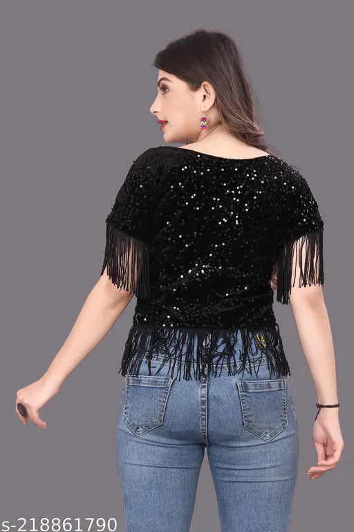 black sequined top with fringe details and jeans wears bright pink earrings.