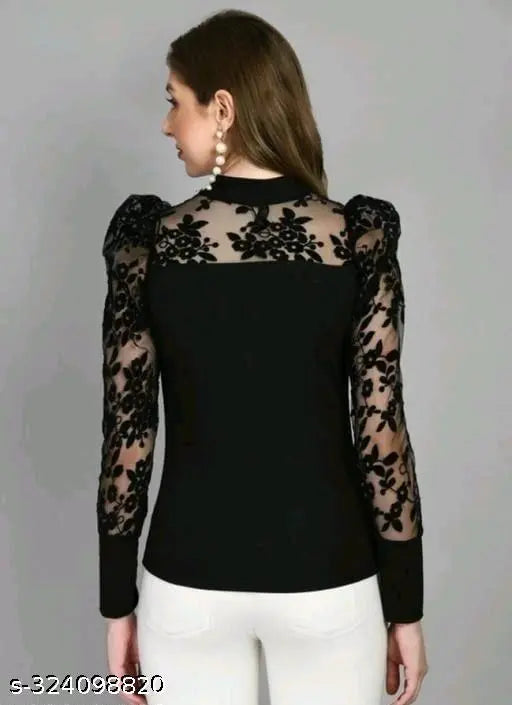 Woman in a black top with floral lace sleeves and sheer detailing, wearing white pants, conveying elegance.