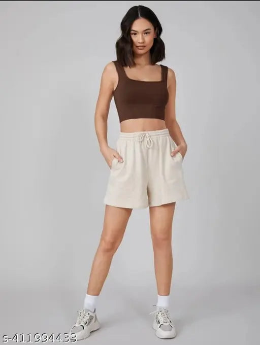  shoulder-length dark hair wears a brown tank top and cream drawstring pants. 