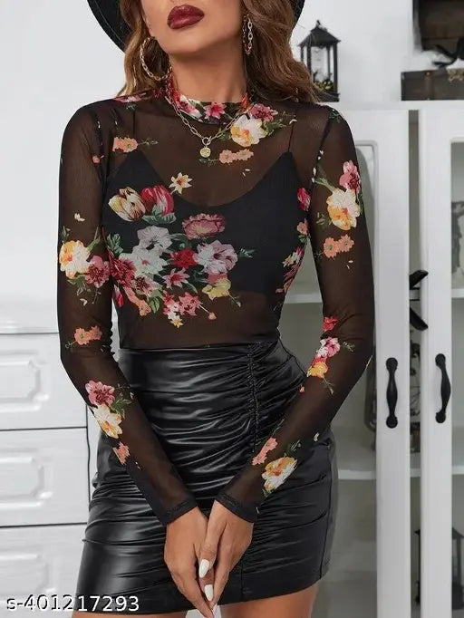 floral-patterned mesh top and black leather skirt stands indoors. Her look is stylish, with bold lipstick