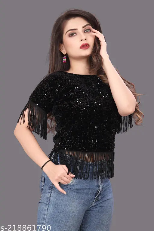 black sequined top with fringe details and jeans wears bright pink earrings.