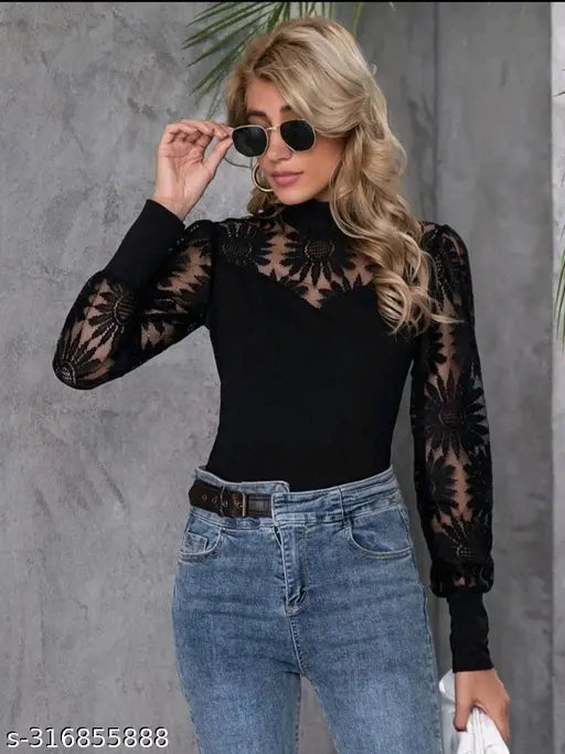  black, sheer floral top and blue jeans. She holds sunglasses, exuding a confident and stylish vibe