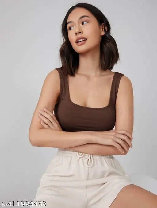  shoulder-length dark hair wears a brown tank top and cream drawstring pants. 